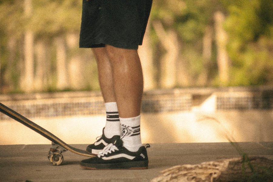 Skateboarder waiting to drop into a bowl, wearing the white Dirty Donny x Mike Vallely Collaboration crew socks.