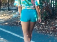 a woman roller skating down a road wearing blue shorts