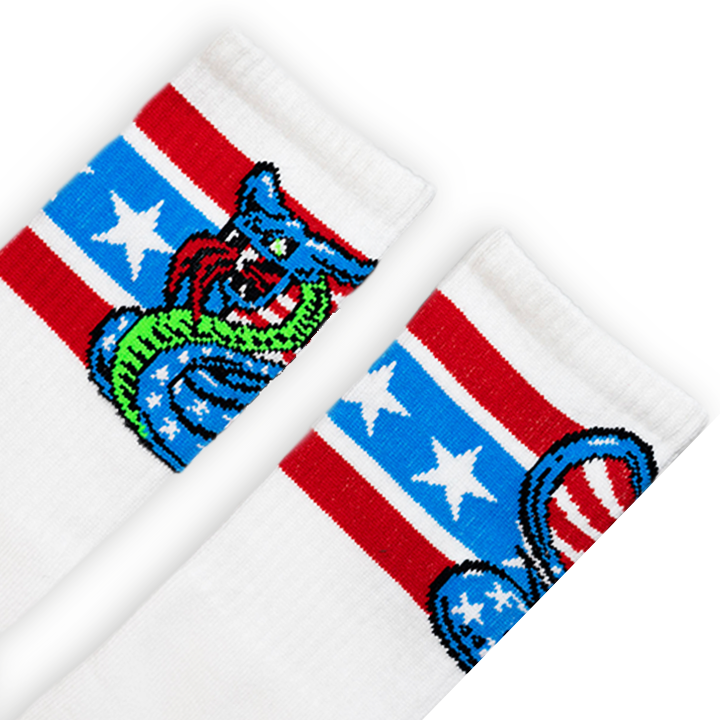 SOCCO x Dirty Donny Cobra Socks. White Crew Socks with three stripes: the top is red, the middle is light blue with white stars, and the bottom is red. 70s style Blue Star Spangles Body with Stripes inside the snake's hood, and an acid green belly. Dirty Donny Logo Signature on the top of the foot.