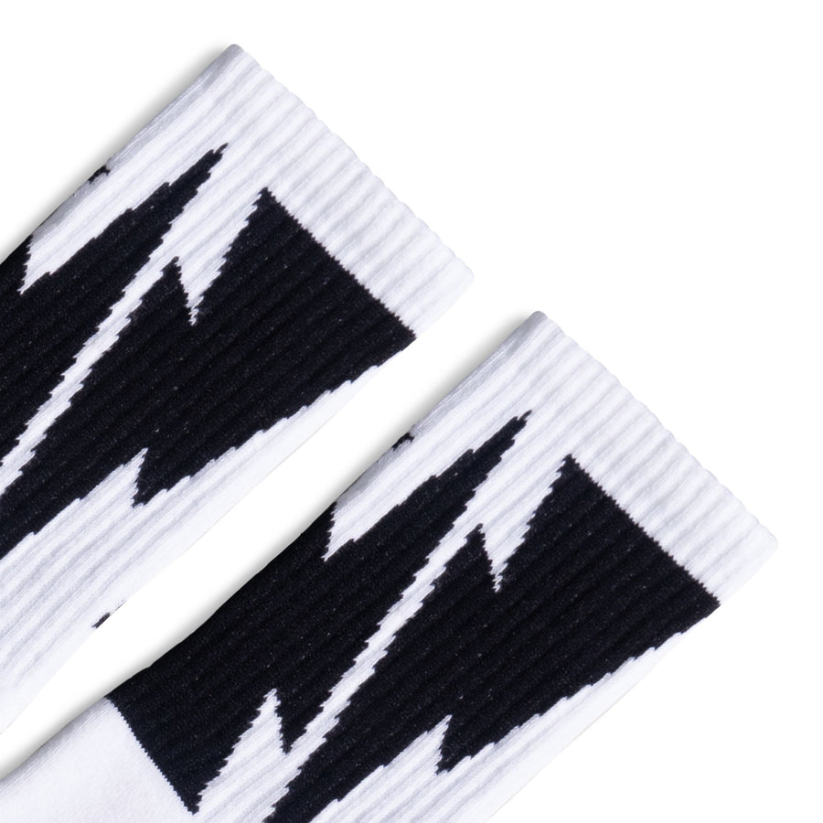 White Crew socks with Large Black Lightning Bolts decorating the leg all the way around. Mike Vallely's Signature knitted into the bottom of the foot.