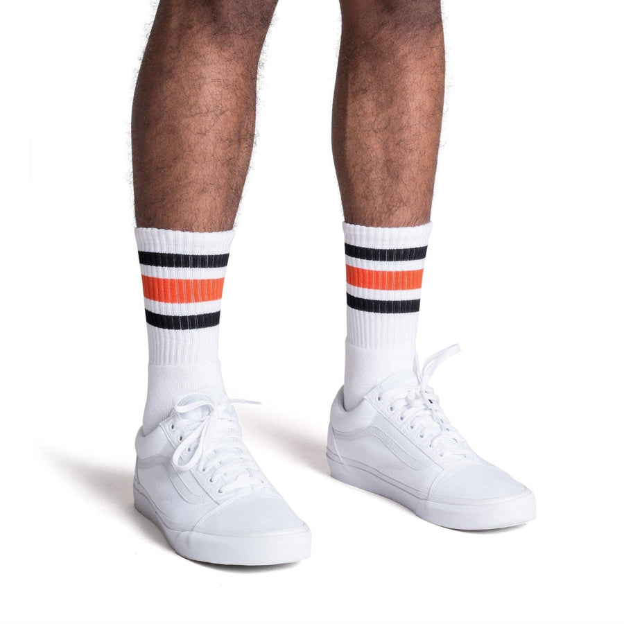 White athletic socks with black and orange stripes on the leg. Made for men, women and children. Crew Sock Length.