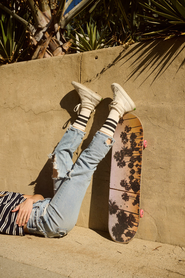 Two boys sitting on steps with a skateboard, wearing SOCCO retro striped socks made from organic cotton.