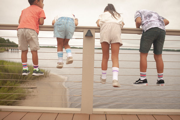 Four kids looking over the pier wearing SOCCO Jr. socks.