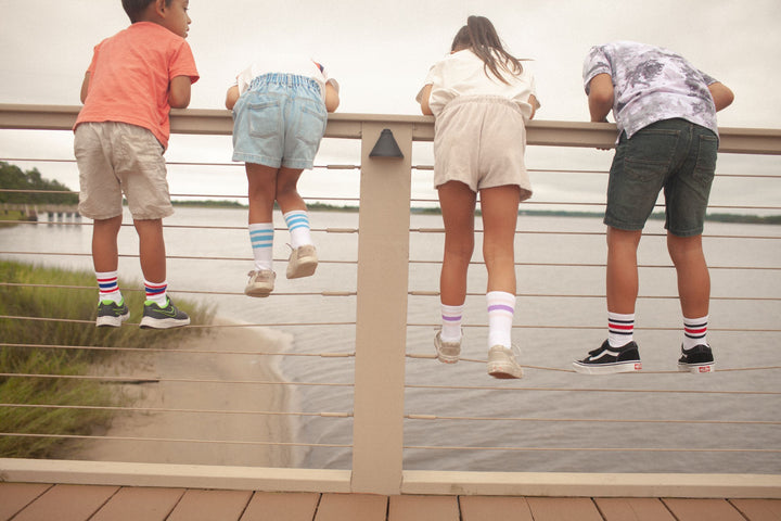 Four kids looking over the pier wearing SOCCO Jr. socks.