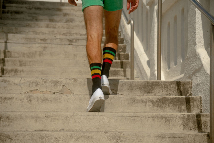 Man wearing Rasta colored SOCCOs walking up the stairs.