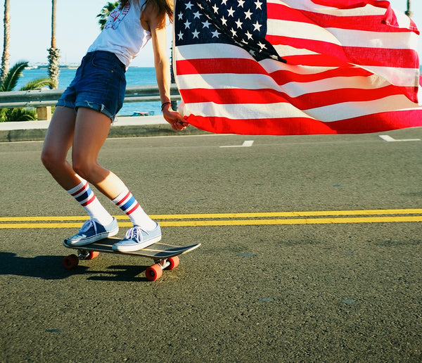 Legs wearing SOCCO socks and roller skated in front of red, white and blue painted concrete wall.