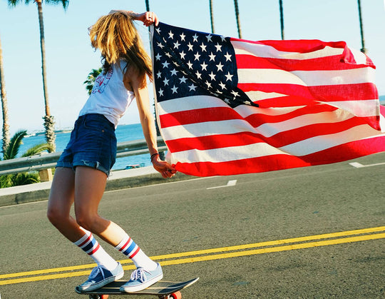 Professional Skateboarder Sierra Prescott skating down the street holding an American flag. 