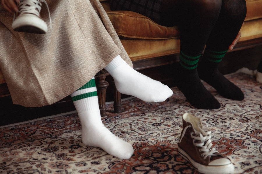 Female wearing white SOCCO socks with green stripes.