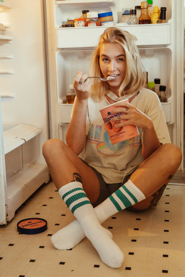 a woman sitting on the floor in front of an open refrigerator