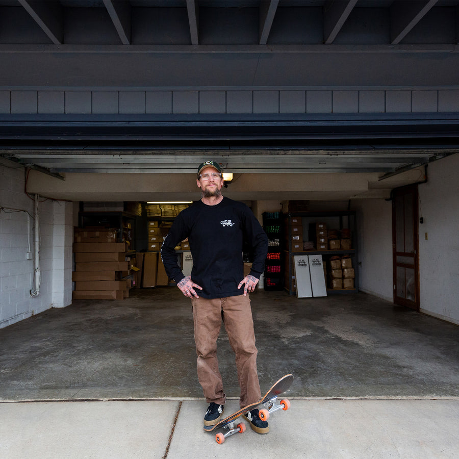 Mike Vallely, one foot on his skateboard, hanging out at home.