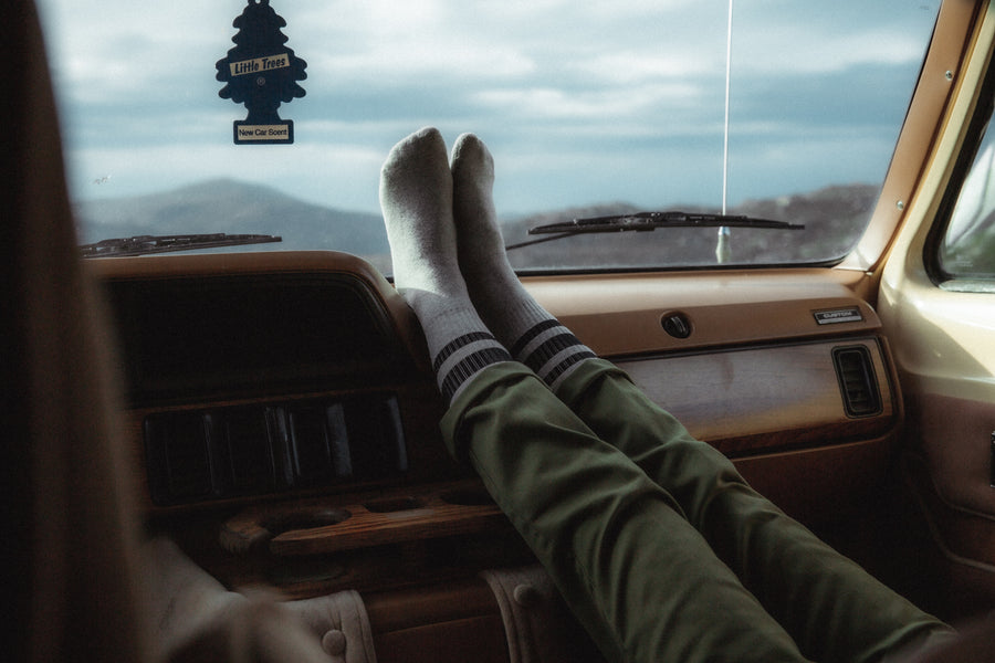 Legs propped up on a van dashboard wearing SOCCO grey socks with black stripes