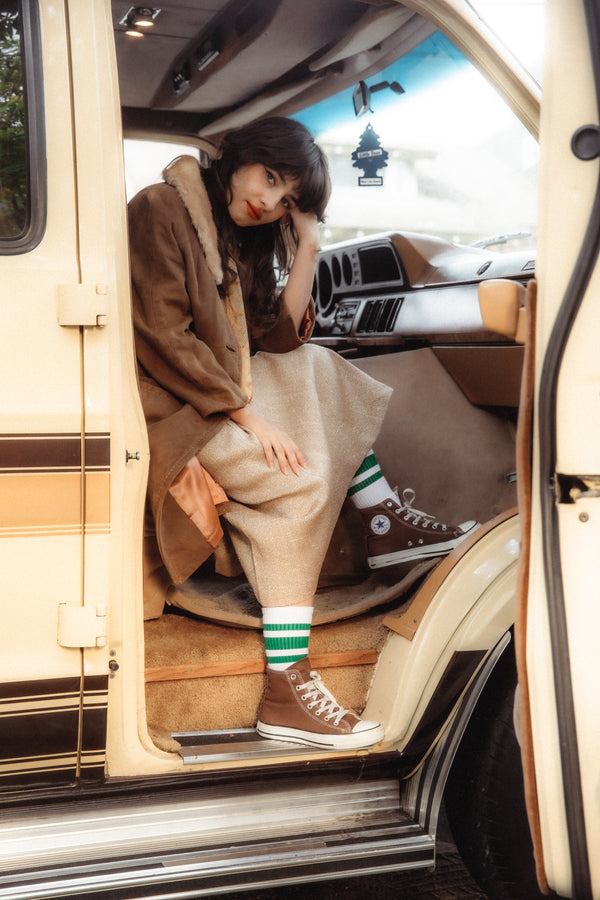 Female wearing white SOCCO socks with green stripes.