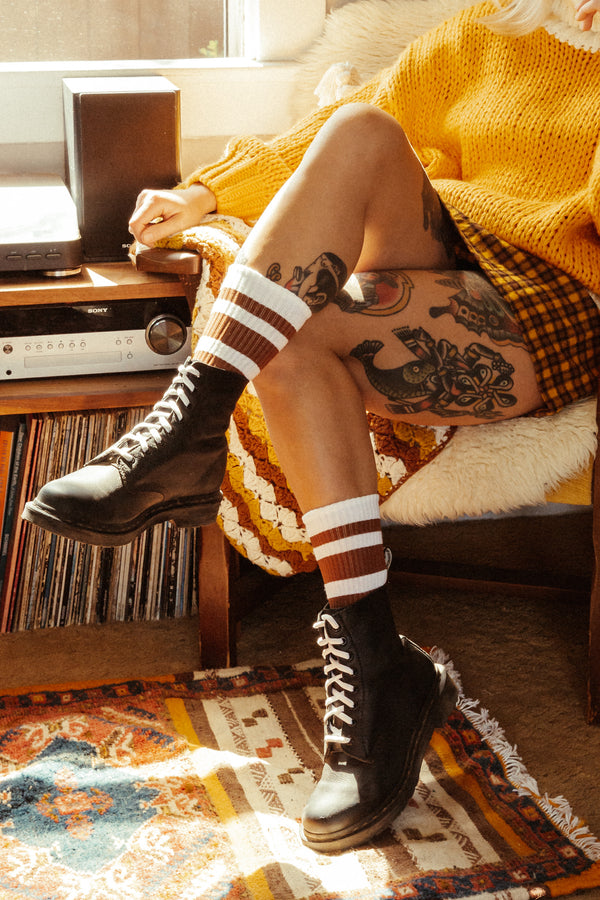 Blonde female wearing brown striped SOCCO socks with Doc Martens Boots