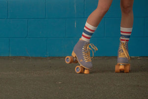 Female wearing red, white, and blue All American SOCCO socks with roller skates.