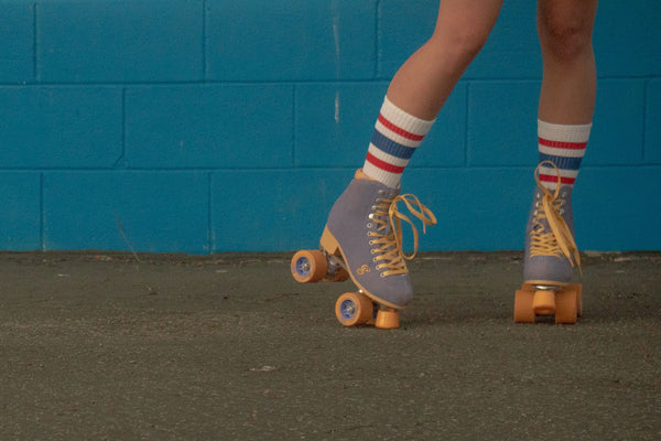 Female wearing red, white, and blue All American SOCCO socks with roller skates.