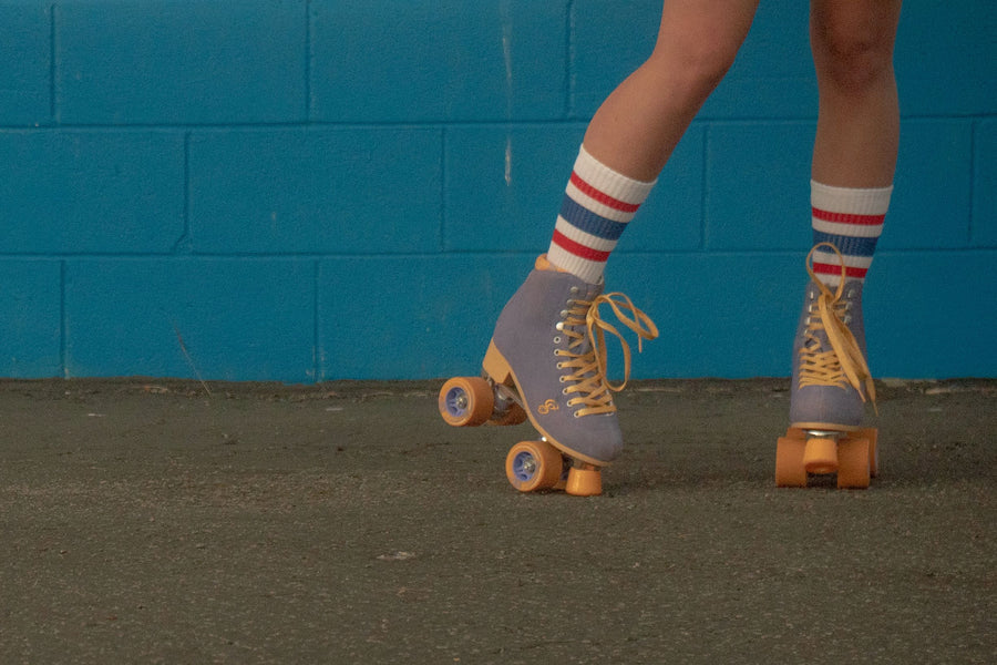 Female wearing red, white, and blue All American SOCCO socks with roller skates.