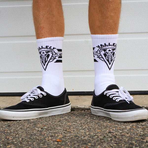 Dirty Donny x Mike Vallely Collaboration Crew Socks. White Crew Socks with 3 black stripes on the leg. Mike Vallely's Elephant V Logo with lightning bolts in an inverted triangle on the front of the leg. "VALELLY" in all caps above the Mike V Elephant Logo.