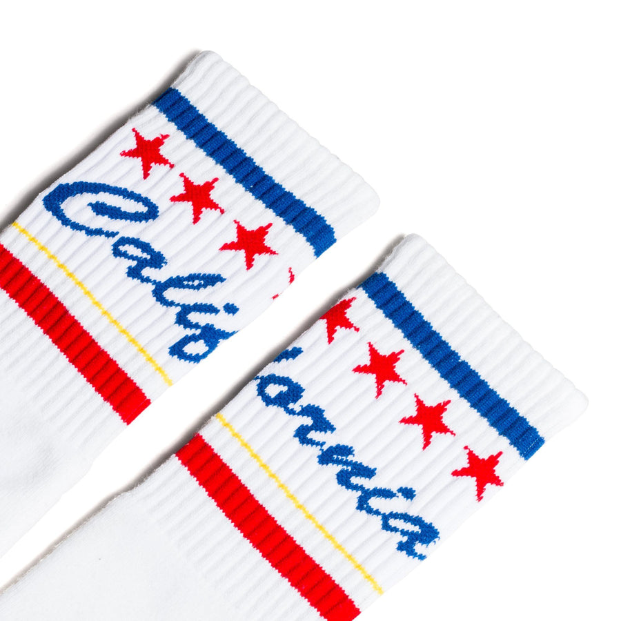 White athletic socks with California text in blue cursive over white and red and blue stripes.