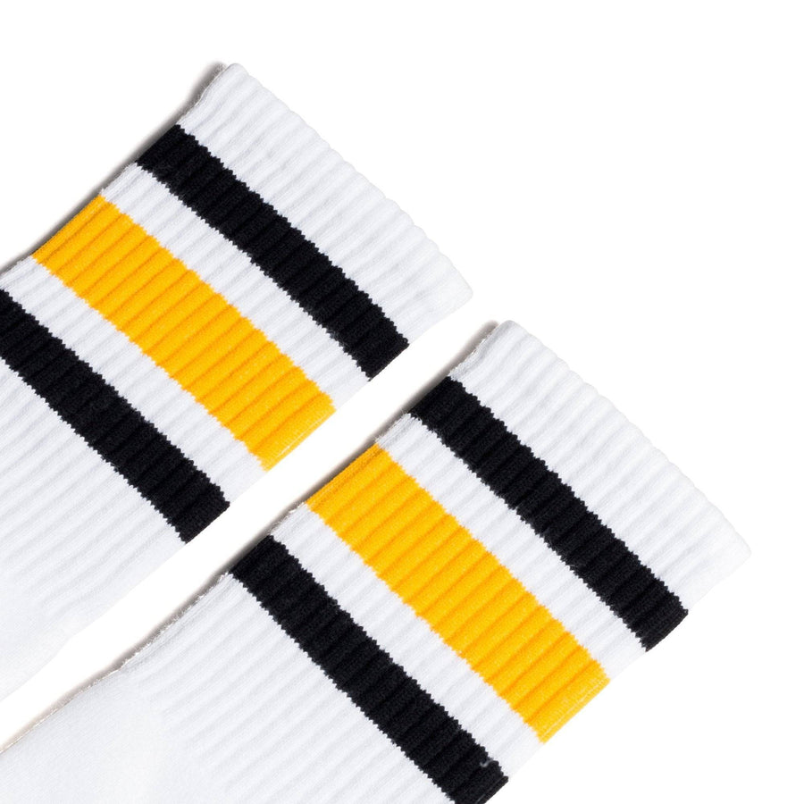 White athletic socks with black and gold stripes on the leg. Made for men, women and children. Crew Sock Length.