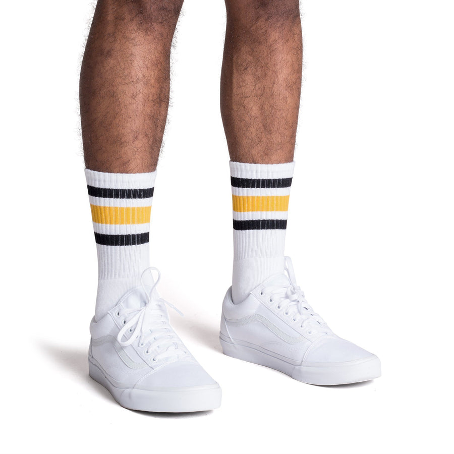 White athletic socks with black and gold stripes on the leg. Made for men, women and children. Crew Sock Length.