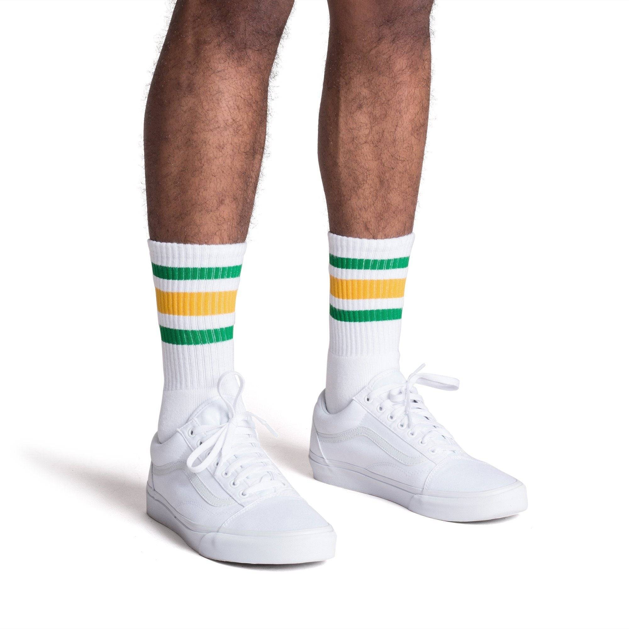 White athletic crew length socks with green and gold stripes for men, women and children.