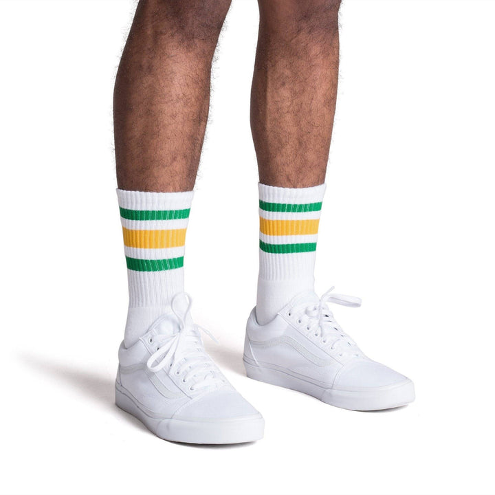 White athletic crew length socks with green and gold stripes for men, women and children.